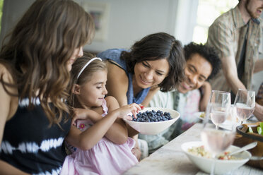 Eine Familie, die sich zum Essen trifft: Erwachsene und Kinder an einem Tisch. - MINF01263