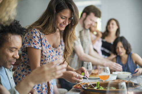 Eine Familie, die sich zum Essen trifft: Erwachsene und Kinder an einem Tisch. - MINF01264