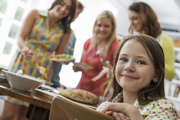 Eine Familie, die sich zum Essen trifft: Erwachsene und Kinder an einem Tisch. - MINF01269