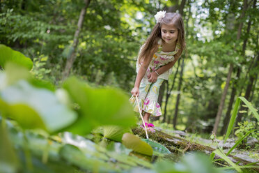 Ein Mädchen spielt an einem Teich in einem Wald. - MINF01310