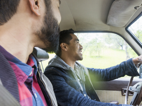 Zwei junge Männer in einem Auto, Fahrer und Beifahrer, lächelnd., lizenzfreies Stockfoto