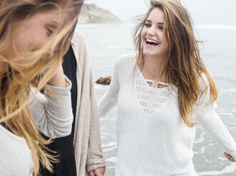 Three smiling young women walking on a beach. - MINF01336