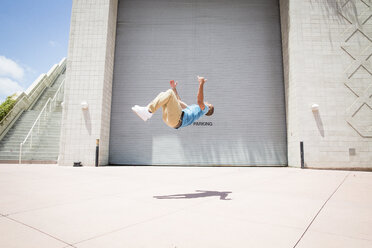 Young man somersaulting in front of a garage door. - MINF01375