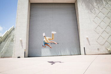 Young man somersaulting in front of a garage door. - MINF01376