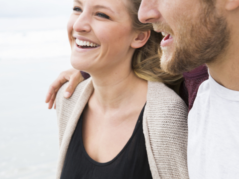 Nahaufnahme eines lächelnden jungen Mannes und einer jungen Frau an einem Strand., lizenzfreies Stockfoto