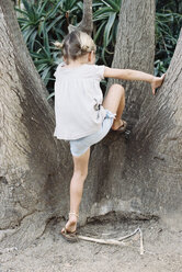 Ein junges, blondes Mädchen klettert auf einen Baum. - MINF01433