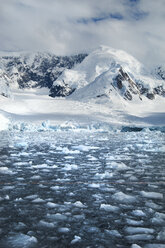 Mountains and snowy landscape reflected in calm sea water. Ice floes on the water. - MINF01459