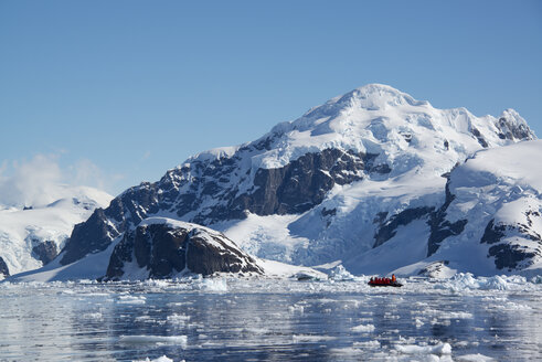 Ein kleines Boot, das zwischen Eisschollen auf dem Ozean schwimmt, vor der Küste einer Insel in der Antarktis. - MINF01462
