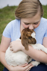 A girl cuddling a baby goat. - MINF01470