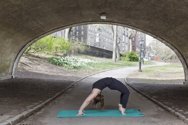 A young woman in Central Park, in a black leotard and leggings, doing yoga. - MINF01476