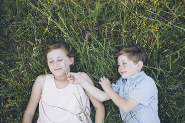 Zwei Kinder, Bruder und Schwester, liegen Seite an Seite im Gras - MINF01491