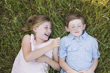 Zwei Kinder, Bruder und Schwester, liegen Seite an Seite im Gras - MINF01492