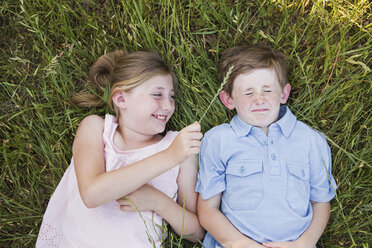 Zwei Kinder, Bruder und Schwester, liegen Seite an Seite im Gras - MINF01493