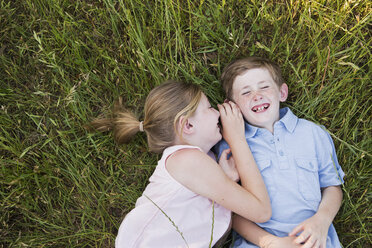 Zwei Kinder, Bruder und Schwester, liegen Seite an Seite im Gras - MINF01494