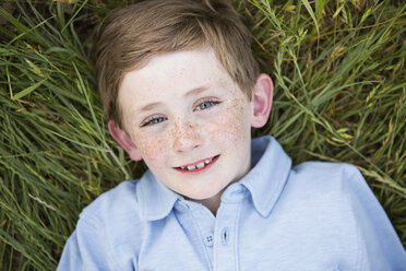 A boy in a blue shirt lying on his back on grass. - MINF01495