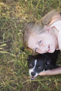 Ein Mädchen, das einen schwarz-weißen Hund im Park umarmt. - MINF01503