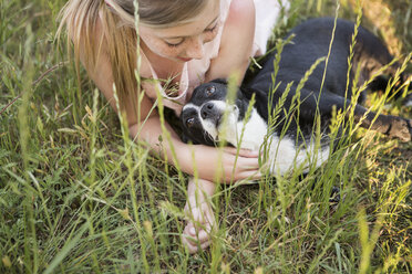 Ein Mädchen, das einen schwarz-weißen Hund im Park umarmt. - MINF01504