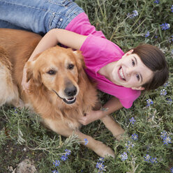 Ein junges Mädchen, das einen Golden Retriever umarmt. - MINF01512