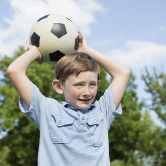 Ein kleiner Junge hält einen Fußball über seinen Kopf. - MINF01520