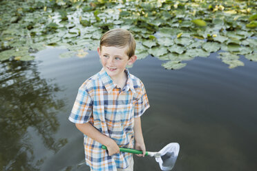 A young boy standing in shallow water with a fishing net. - MINF01522