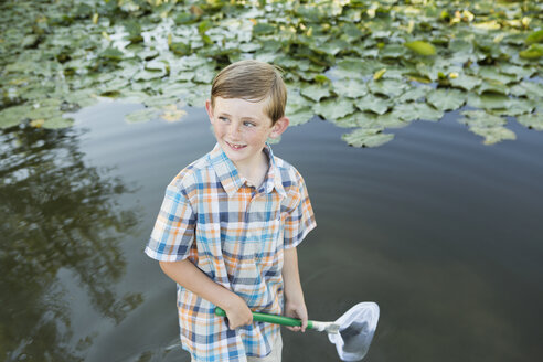 Ein kleiner Junge steht mit einem Fischernetz im flachen Wasser. - MINF01522