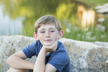 Head and shoulders portrait of a young boy sitting with his chin resting on his hand. - MINF01531