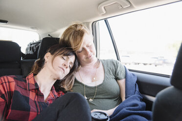 Zwei Frauen in einem Auto auf einer Reise, beide schlafend auf dem Rücksitz, die Köpfe zusammen. - MINF01619