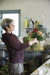 Organische Blumenarrangements: Eine Frau bindet einen Blumenstrauß von Hand. - MINF01661