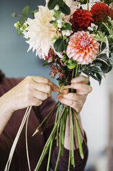 Organische Blumenarrangements: Eine Frau bindet einen Blumenstrauß von Hand. - MINF01662