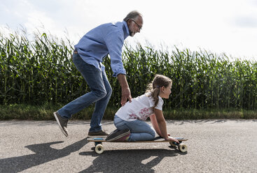 Älterer Mann hilft kleinem Mädchen, Skateboardfahren zu lernen - UUF14561