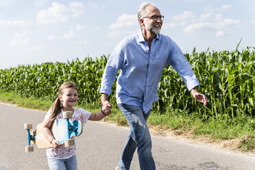 Älterer Mann und kleines Mädchen laufen lachend auf der Straße - UUF14562