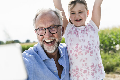 Älterer Mann und kleines Mädchen machen lustige Selfies auf dem Feld - UUF14574