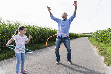 Großvater und Enkelin spielen mit Hoola Hoop auf der Straße - UUF14578