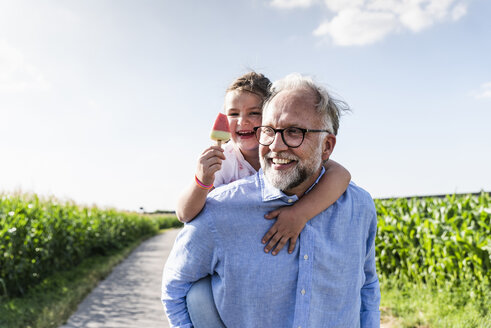 Grandfather carrying granddaughter piggyback - UUF14579