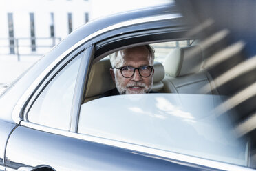 Mature businessman sitting on backseat in car, looking out of window - UUF14644