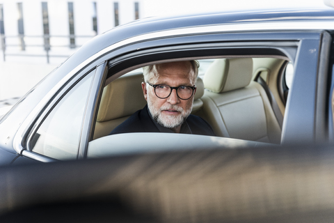 Mature businessman sitting on backseat in car, looking out of window stock photo