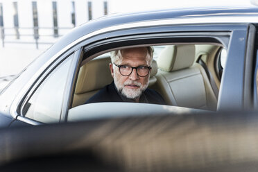 Mature businessman sitting on backseat in car, looking out of window - UUF14645