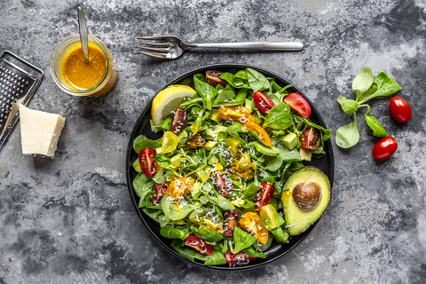 Salad with lamb's lettuce, tomatoes, avocado, parmesan and curcuma lemon dressing stock photo