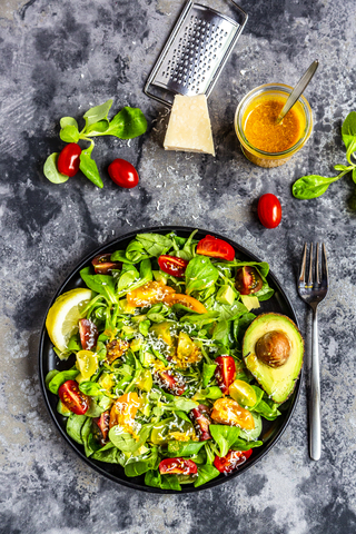 Salad with lamb's lettuce, tomatoes, avocado, parmesan and curcuma lemon dressing stock photo