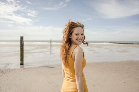 Porträt einer rothaarigen Frau, die fröhlich am Strand lacht, lizenzfreies Stockfoto