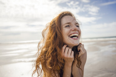 Porträt einer rothaarigen Frau, die fröhlich am Strand lacht - KNSF04221