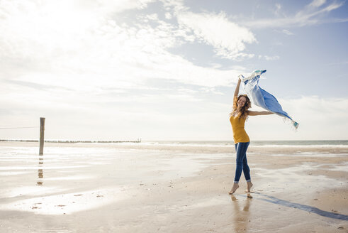 Happy woman having fun at the beach, dancing and swaying towel - KNSF04225