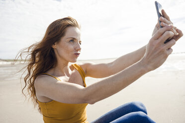 Redheaded woman taking smartphone selfie on the beach - KNSF04228