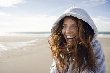 Frau, die sich an einem windigen Strand vergnügt, mit Kapuze - KNSF04229