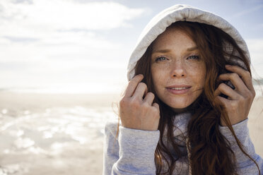 Woman wearing hood on a windy beach - KNSF04230