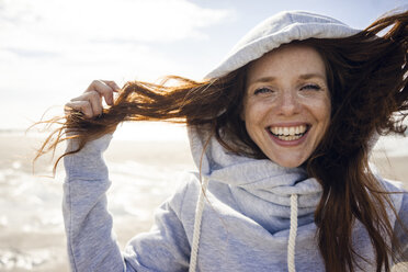 Woman having fun on a windy beach, wearing hood - KNSF04231