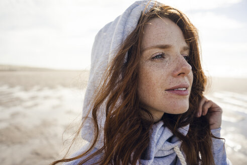 Woman wearing hood on a windy beach - KNSF04234