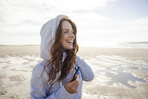 Woman having fun on a windy beach, wearing hood stock photo