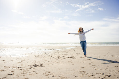 Happy woman having fun at the beach, running at the sea - KNSF04237