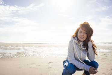 Redheaded woman relaxing on the beach, crouching - KNSF04238